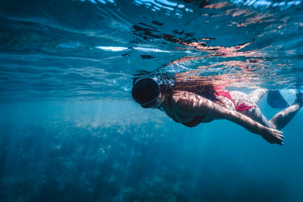 A woman wearing a bikini snorkeling in the clear blue sea underwater exploration.